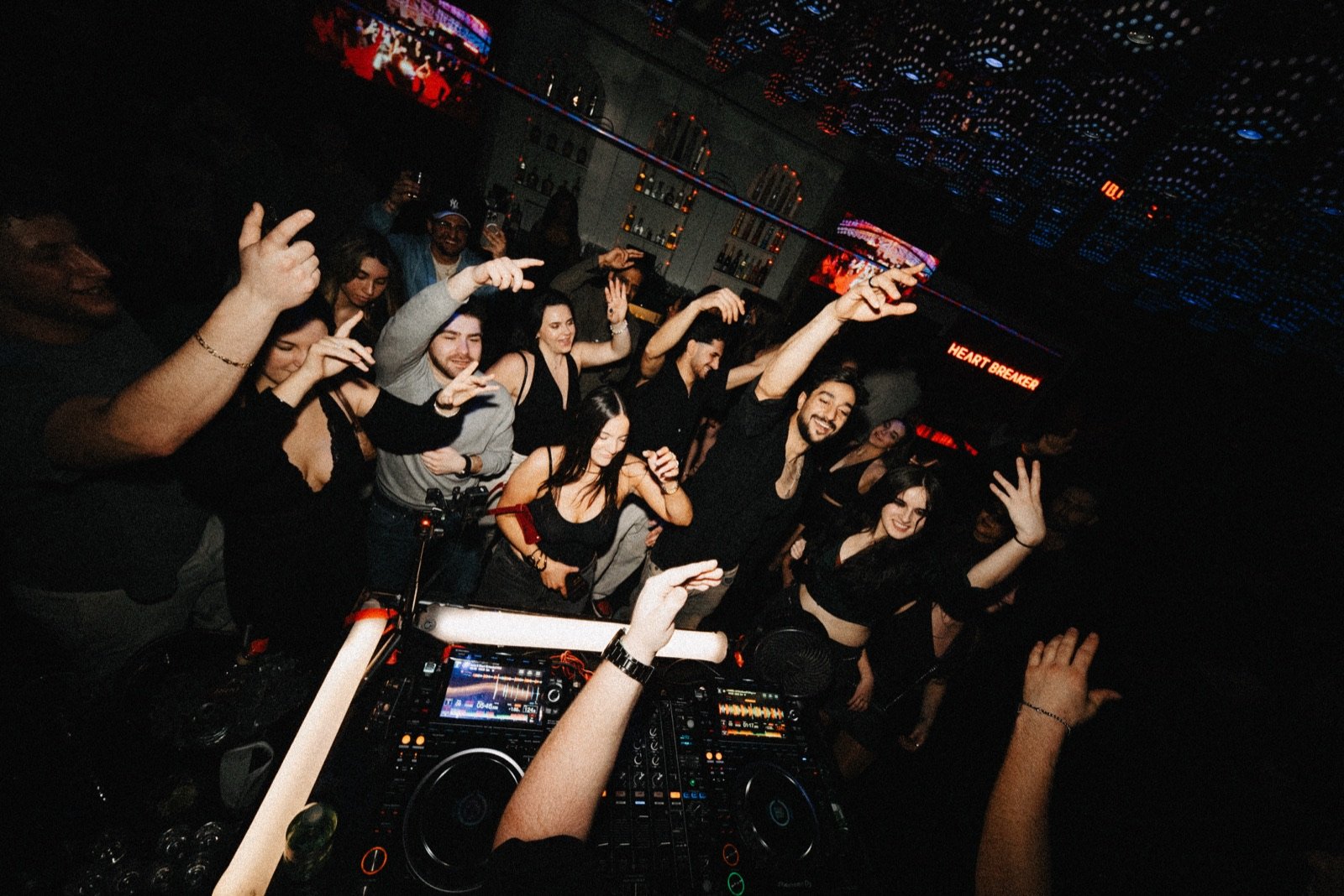 Crowd with hands up viewed from the DJ booth